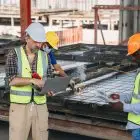 Three Men In Safety Vests Are Standing In Front Of A Large Metal Structure