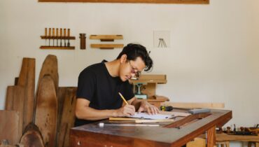 A contractor filling out paperwork at a workbench, tracking project details and filing deadlines.