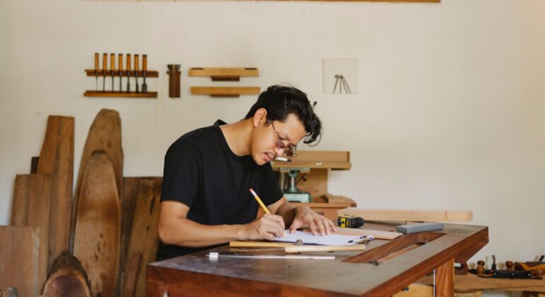 A contractor filling out paperwork at a workbench, tracking project details and filing deadlines.